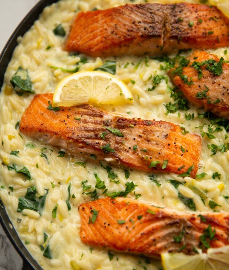 salmon boursin orzo in large pan garnished with lemon wedges and fresh parsley