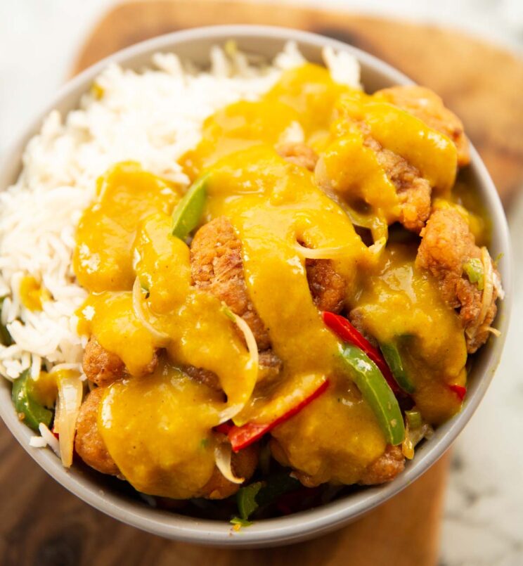 salt and chilli chicken served in a bowl with curry sauce drizzled on top