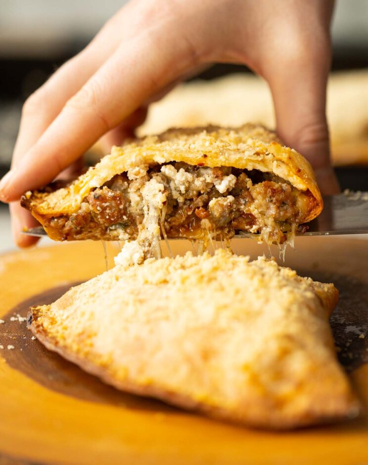 side shot of hand lifting half tortilla calzone showing filling and cheese pull