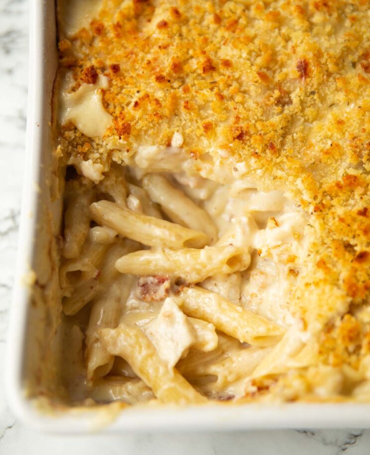 close up shot of chicken and bacon pasta bake with scoop taken out