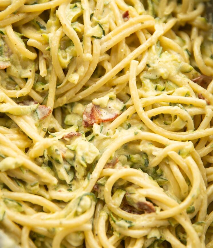 close up overhead shot of creamy courgette bacon pasta in pan