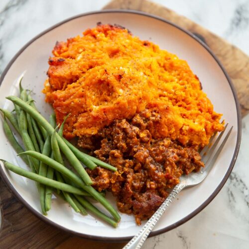 spiced sweet potato shepherds pie served on small white plate with green beans
