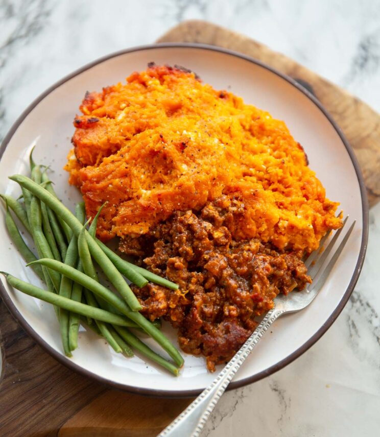 spiced sweet potato shepherds pie served on small white plate with green beans