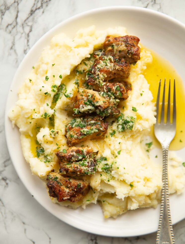 overhead shot of garlic parmesan chicken on bed of mashed potato on small white plate