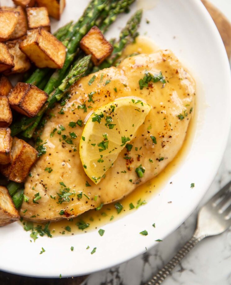 honey lemon chicken breast on small white plate with asparagus and roast potatoes