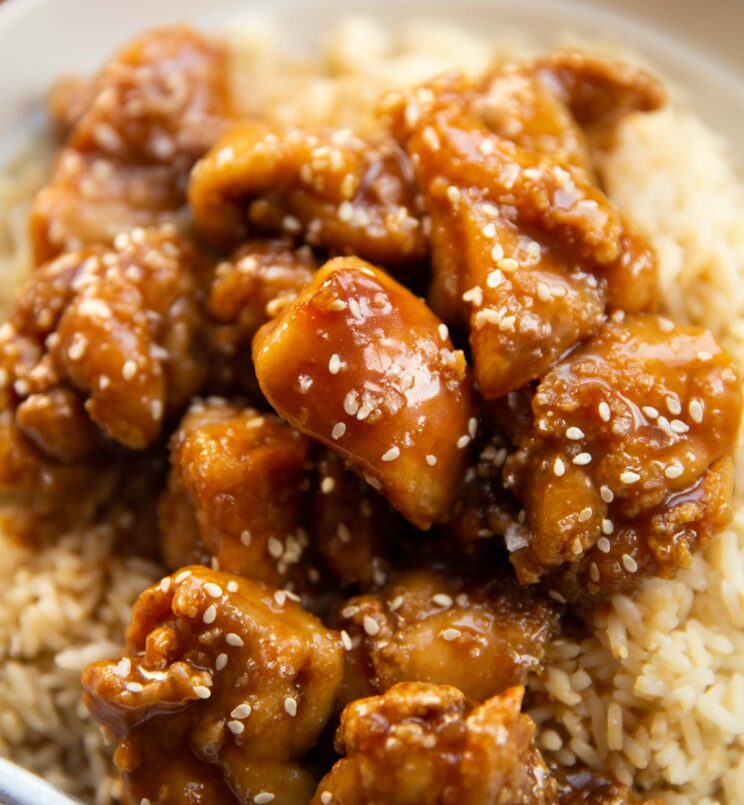 close up shot of salted caramel chicken on bed of rice garnished with sesame seeds